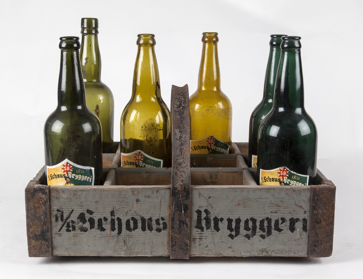 Ølkasse fra Schous bryggeri. Jernhank og jernbånd i bunn og hjørner. Sjablonmalt tekst.