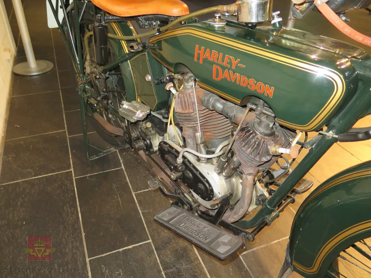 Harley-Davidson 23 F. Motorsykkel, grønn (Brewster Green) med gull staffering og rød påskrift på tanken. Brunt sete. Motoren har betegnelsen F fra fabrikken, det er en 2-sylindret, bensindrevet forbrenningsmotor med et volum på 986 ccm. Motortypen har magnet tenning og standard kompresjon. Tre sitteplasser originalt men kun to etter at sidevogna ble fjernet.