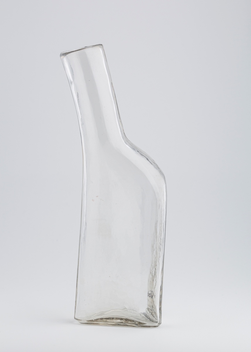Bekkenet er en avlang flaske med tre kanter og langsgående grunnflate, dvs. at flasken ligger. Fra den ene kortenden stikker det en tut med en vid åpning ytterst. Den står skrått på flasken.