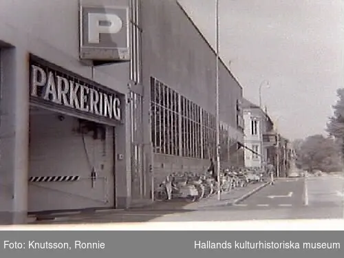 Domus parkeringshus i Halmstad. Fotot visar infarten till parkeringshuset och längs fasaden står en räcka cyklar parkerade.
Bild i samband med miljövårdsutställningarna med bl a, "Miljön i Halland", som visades på museet, 1970-07-03--07-26."