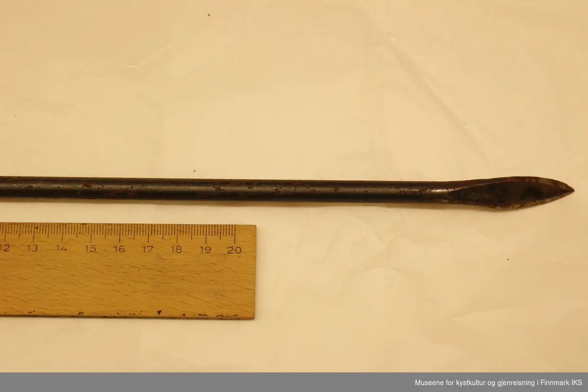 Halvmeter lang jernstang 1cm i diameter, med nåløye i ene enden og bøyd spiss i motsatt ende