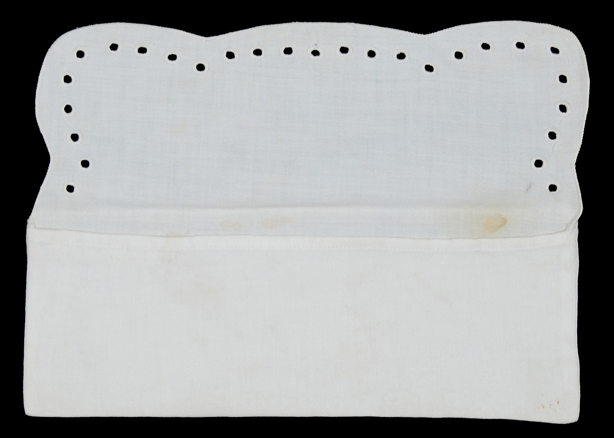 Av vit bomullsväv s.k. angolaväv, kuvertmodell med övervikt lock, en rad kantsydda hål runt locket.