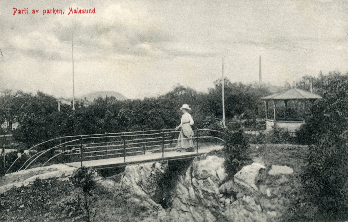 Motiv fra parken i Ålesund med paviliong og en gangbro. En kvinne står på broa.