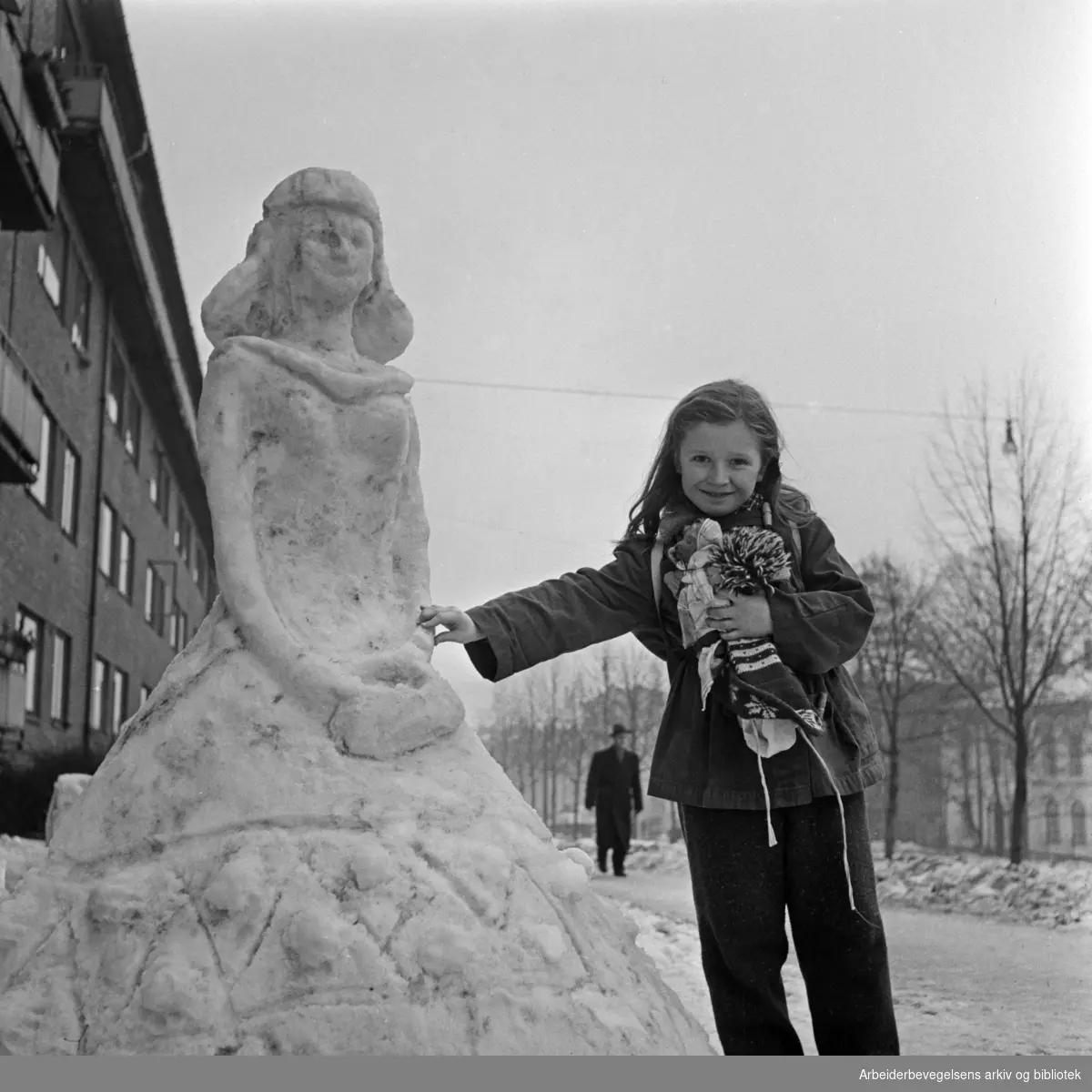 "På hjørnet av Ole Bulls gate og Chr. Michelsens gate har noen laget denne flotte snøskulpturen. Den vekker daglig stor beundring hos forbipasserende. På bildet ser vi Lise Gun Wagle ved siden av kunstverket. " Vinteren 1958.
