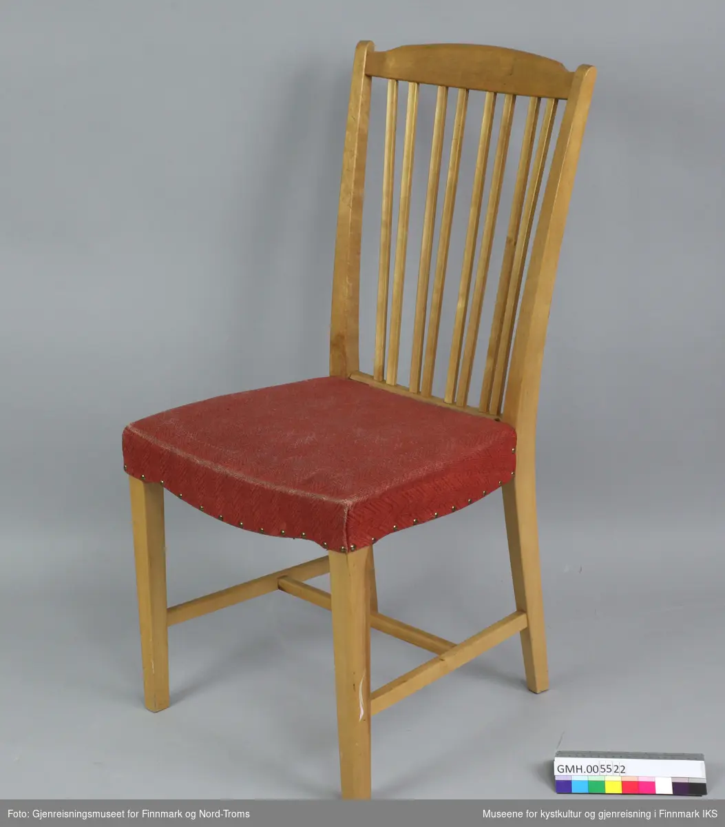 Stolen er bygget i tre med åtte profilerte, flate spiler i ryggen som er plassert to og to. Ryggen er svakt buet og har et buet tverrstykke oppe. Sidestolpene på ryggen danner også bakbenene til stolen. De buer innover fra topp til setet og utover fra setet til gulvflaten. Benene er firkantede og frambenene er rette. Stolen har sidesprosser og en tverrsprosse i midten, mellom sidesprossene.Setet består av en tynn polstret kryssfinérplate og har et rødt, vevd trekk med fiskebensmønster. Trekket er festet med nagler på sidene og bak mot ryggen.