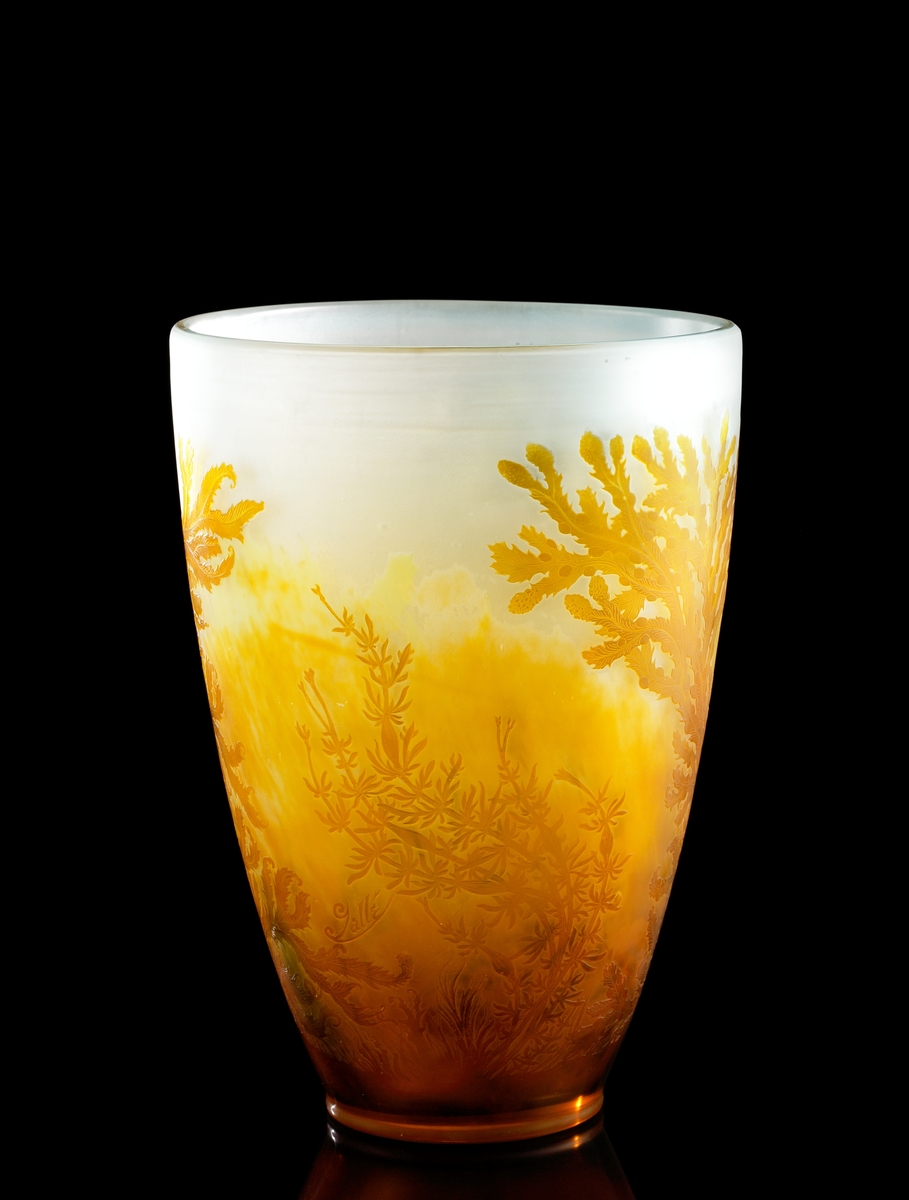 Halvopak, vit vas med etsat överfång i gul-orange nyanser. Växtmotiv föreställande havstång.