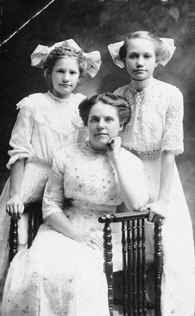 Bak f. v. Carrie og Christina. Dei er barnebarna til Ole Johannes Ree (1841 - 1918). Personen som sit framme er ukjent.