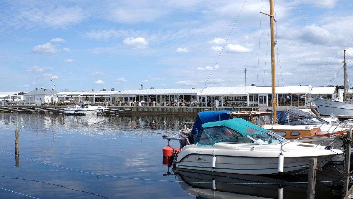 Hamnen i Jönköping. Småbåtar ligger förankrade vid bryggan i Vättern och utmed piren ligger olika restauranger som är öppna sommartid.