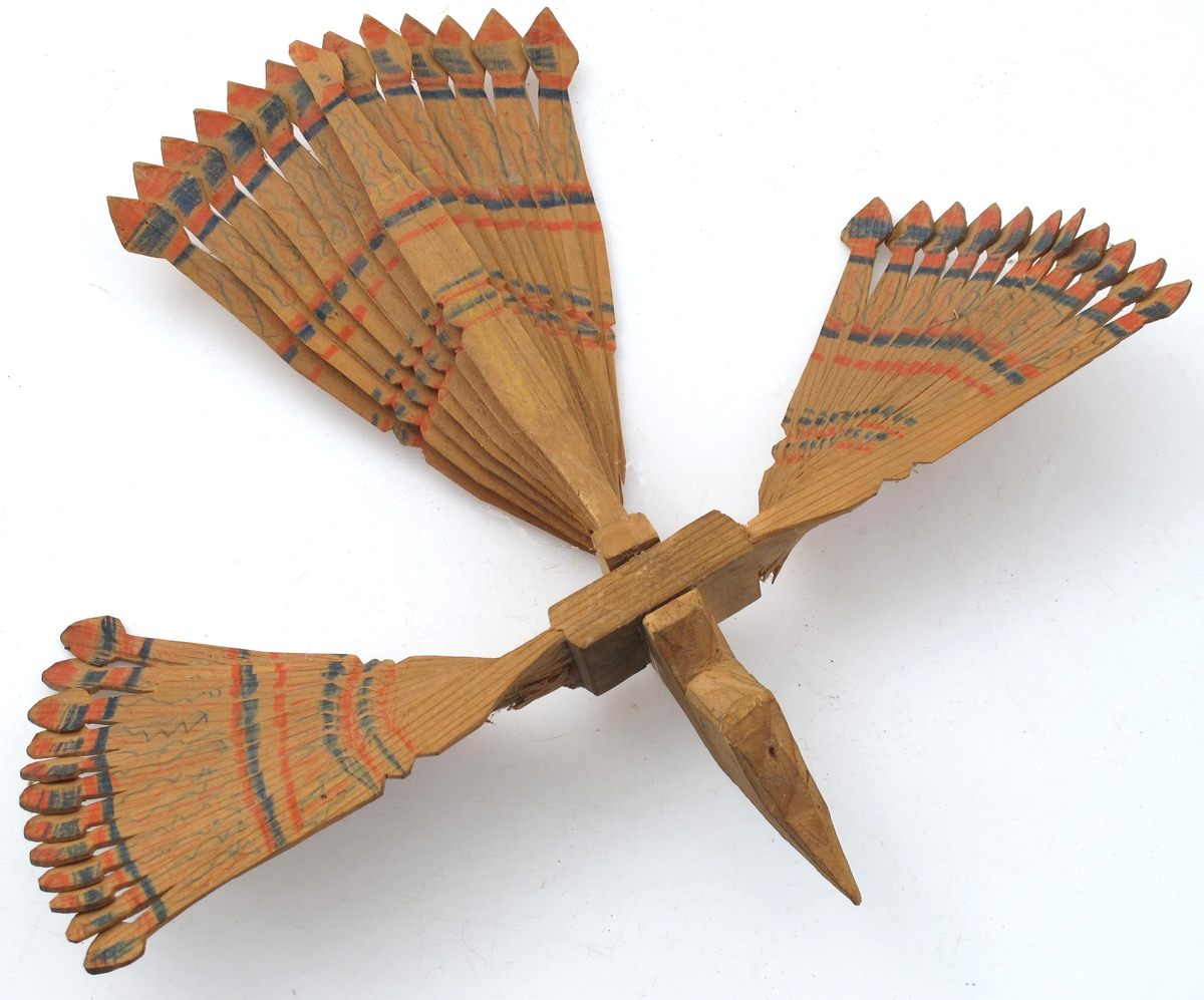 Sponfugl, laget av to stykker tre som er splittet opp til vinger og haleparti, og tilskåret som fuglens hode. Malt med vannfarger.