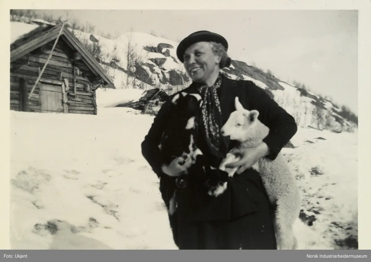 Signe Jarandsen i snøen på gården Skinnarland på Møsstrond. Hun holder et lam som spiser på skjerfet hun har rundt halsen