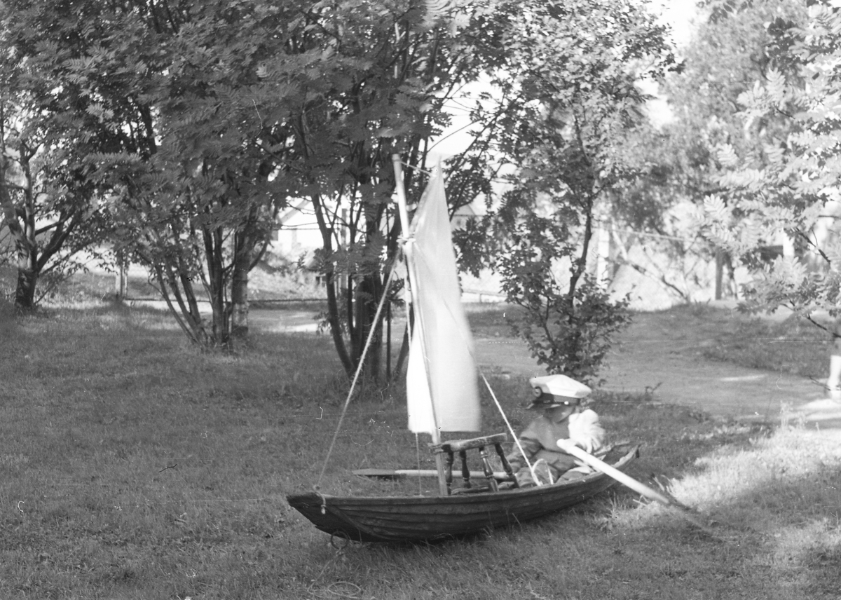 Unge i lekebåt på en gressplen.