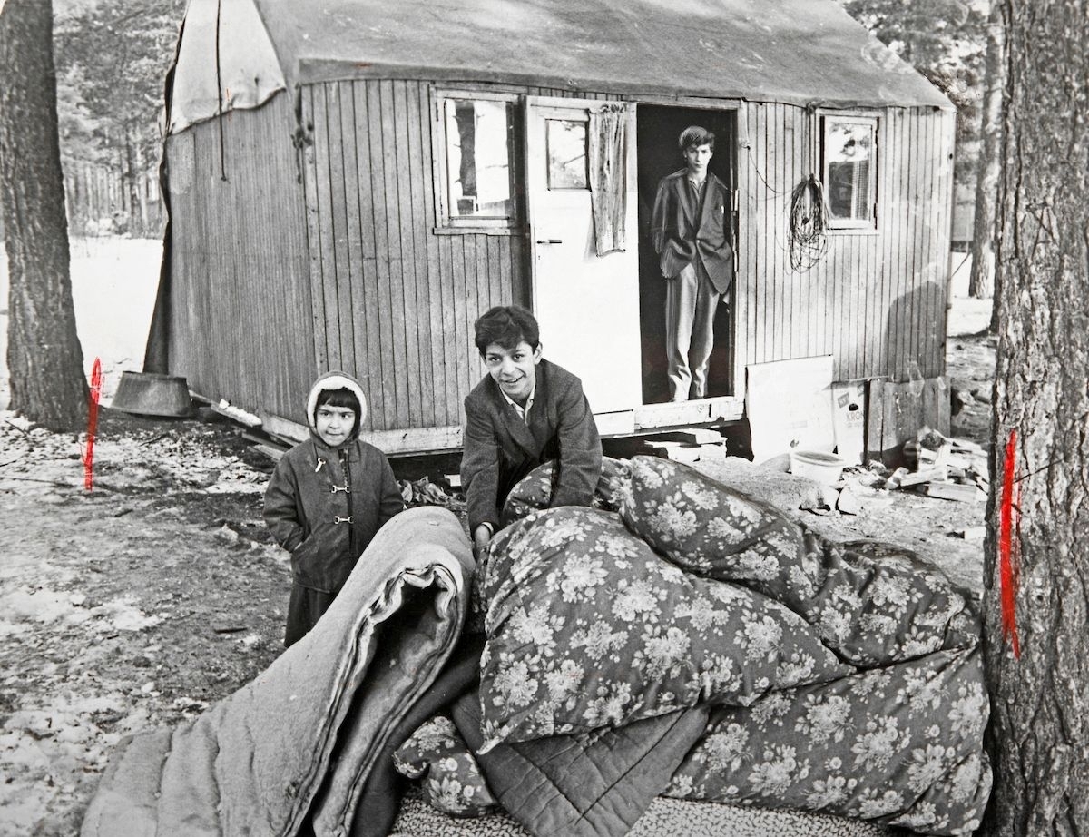 BIlden är tagen i samband med en vräkning av romer i Lilla Sköndal, Stockholm år 1959. Vid Lilla Sköndal har romska boplatser i olika former funnits åtminstone sedan år 1943, då staden iordningsställde en lägerplats. Lägret låg då vid en bergsknalle vid Skogskyrkogårdens södra del och år 1944 bodde här ett trettiotal personer. De boende fick hämta vatten hos några boende i närheten.