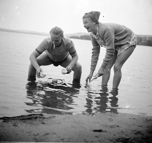 Två vuxna som diskar porslin i en sjö.