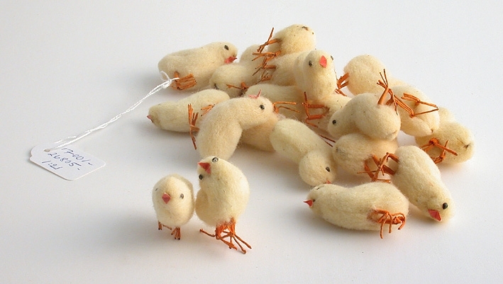 En förpackning med kycklingar, rymmer 21 stycken. Gula i vadd med orange ben av ståltråd.