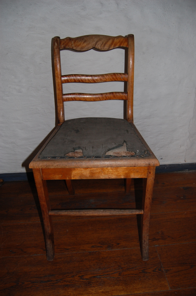 Trestol med sete trukket i kunstskinn (?). Tre ryggsprosser, den øverste profilert. Likner AS.613-617, Biedermeier-stil. Rift i setetrekket.