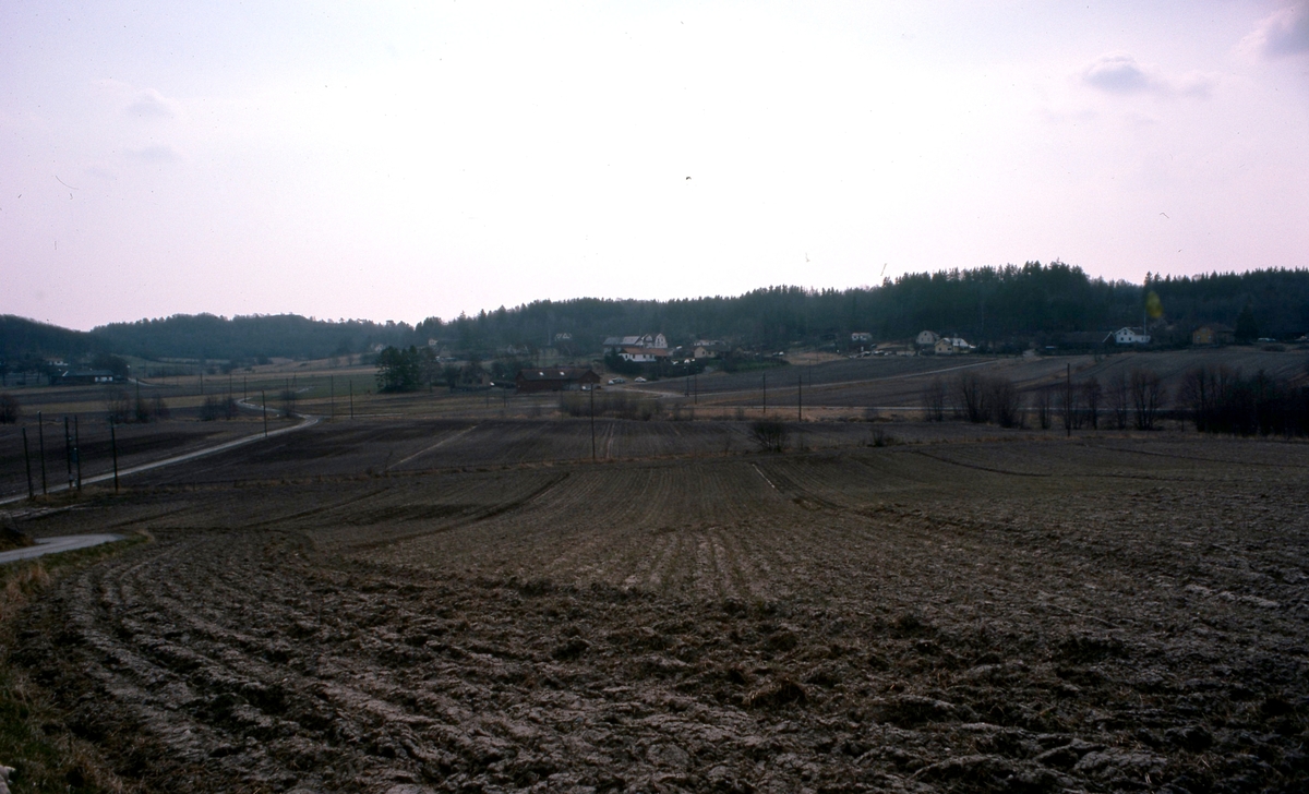 Vy över odlingsmark utefter Heljeredsvägen och Heljeredsgården år 1978. Flera gårdar samlade i Heljered. Sandsjöbacka naturreservat ses i bakgrunden.
