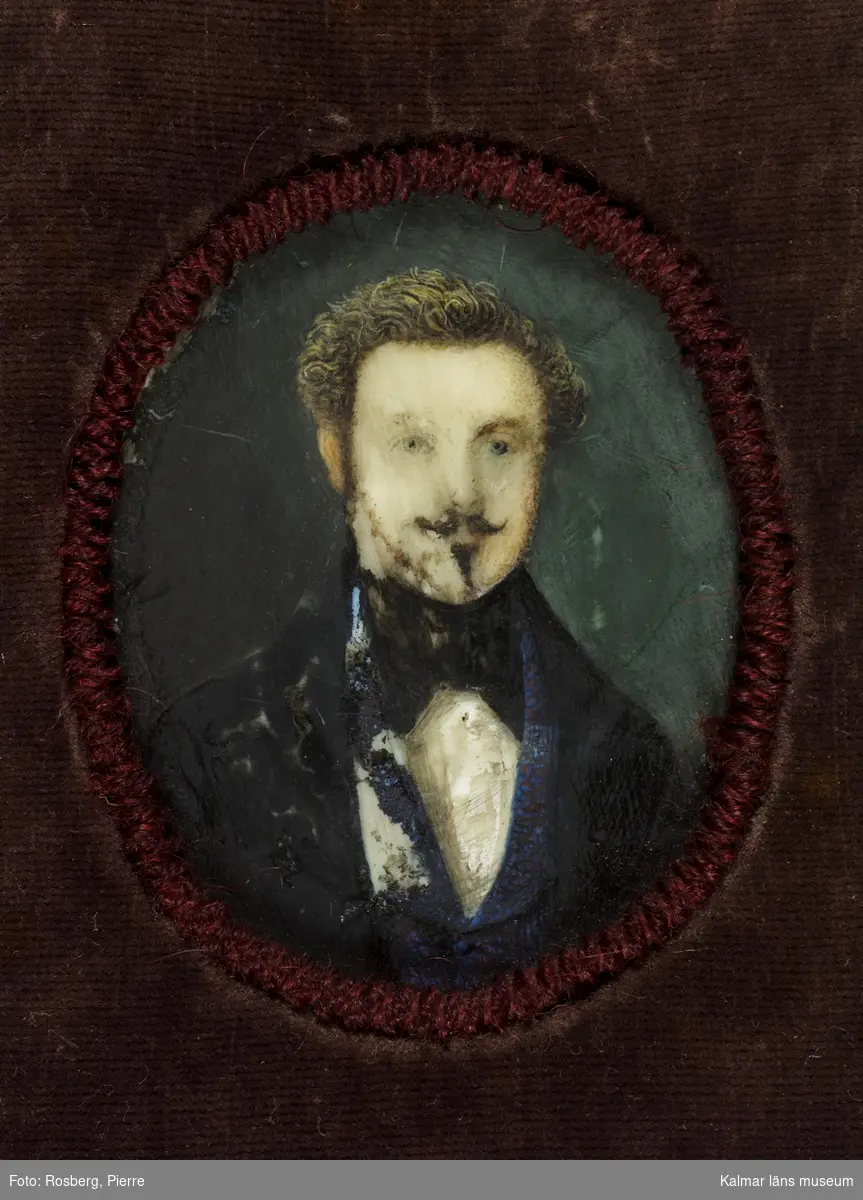 Porträtt, självporträtt av Sven Gustaf Lindblom, fanjunkare, ritlärare och konstnär. Litet porträtt i oval. Man med lockigt bakåtkammat hår, mustaschprydd och med smalt pipskägg.