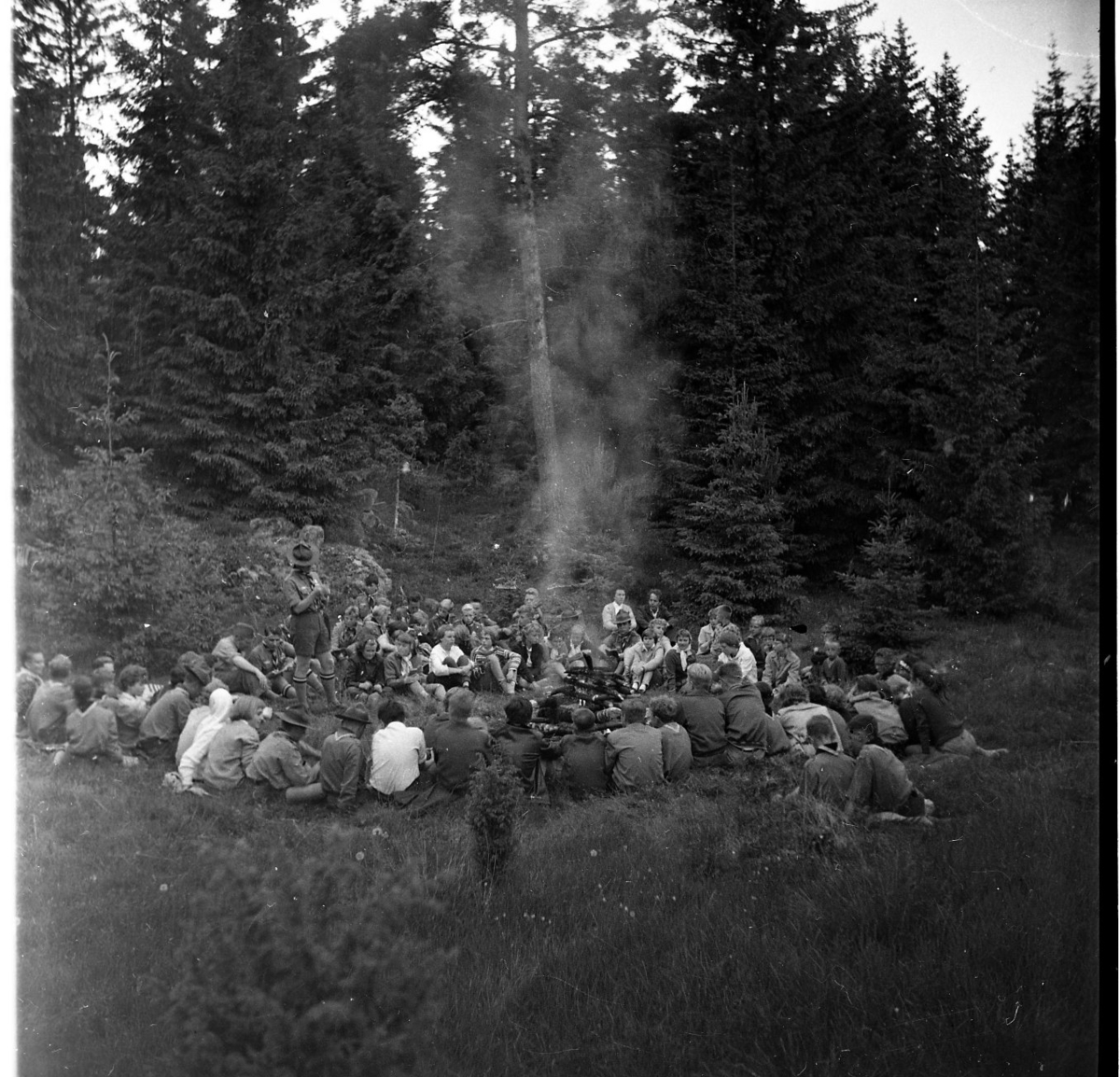 Scouter samlade runt en lägereld, möjligen i Alviken.