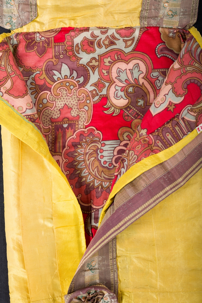 Gul dåppose av silke med dekor av bånd og fryns.