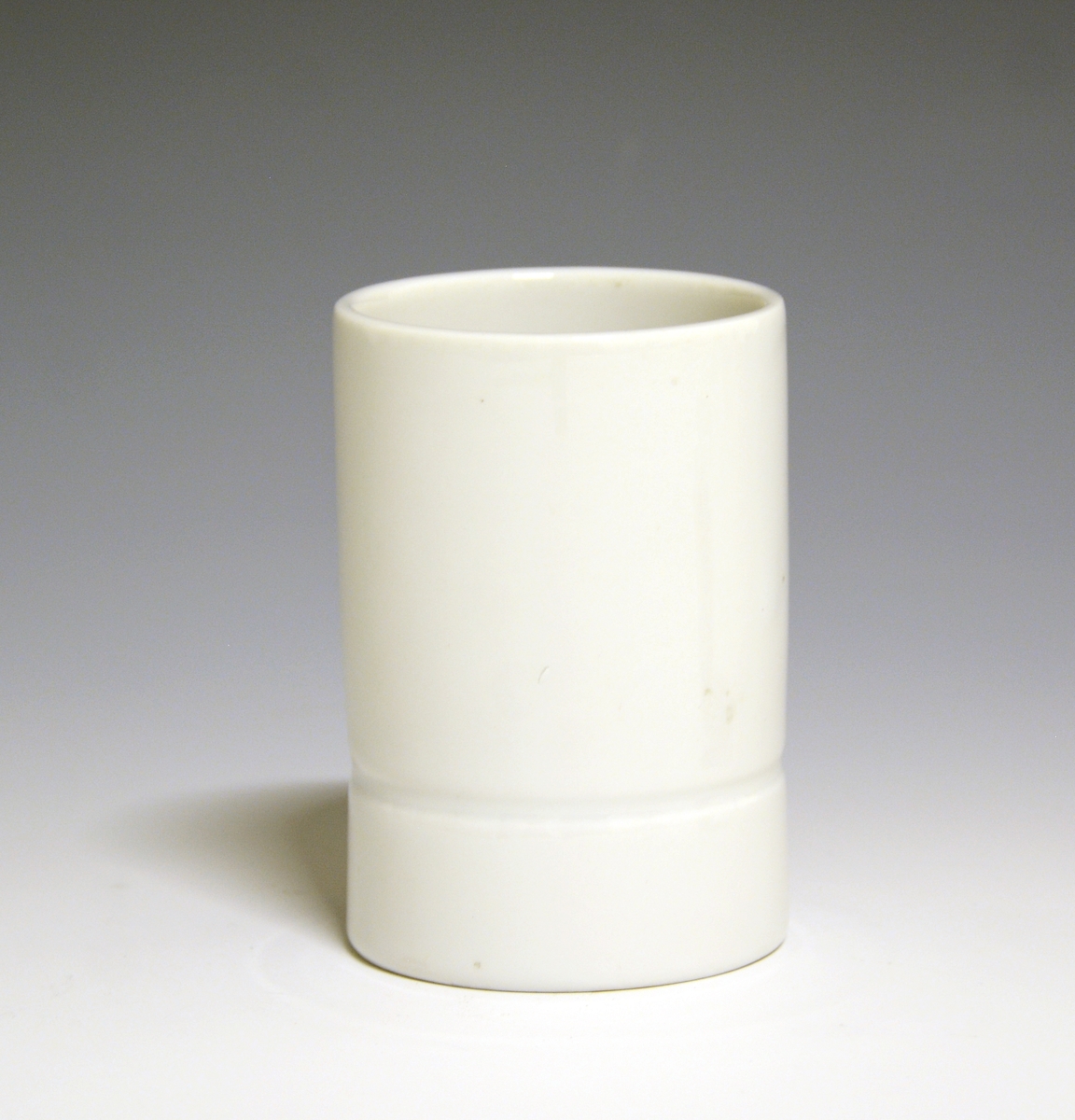 Vase og telysholder av porselen. Fungerer som lysestake den ene veien og vase den andre veien. Sylinderformet med en inntrapping i overgangen mellom vase og telysholder. Hvit glasur. . Ustemplet.
Design: Grete Rønning.
