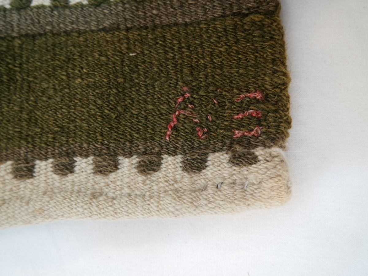 Teppet er vove i ei breidd, falda i endane. Fjølrøysåkle med to ulike mønsterrapportar.
