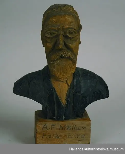 Träskulptur föreställande A. F. Möller, Falkenberg. På fyrkantig sockel. Utförd av John Johansson, Harplinge.