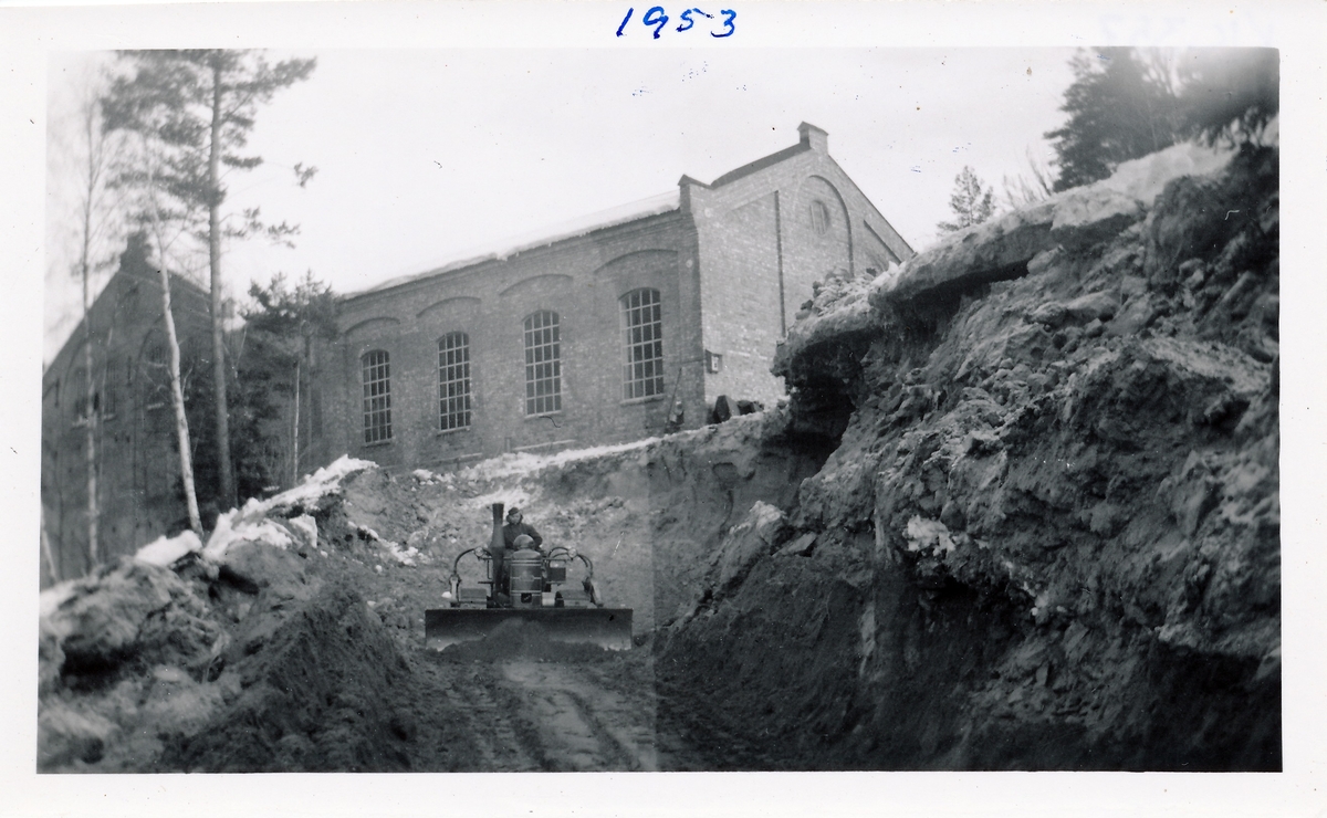 Tomt graves ut for å bygge kraftstasjonen Kistefoss II ved siden av det eldste tresliperiet. Mann på bulldoser jobber med jordmassene.