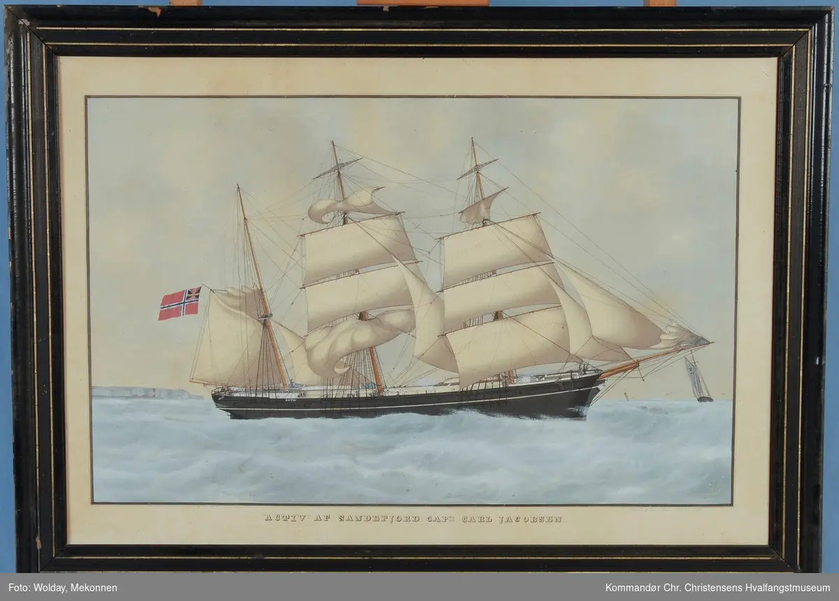Bark ACTIV av Sandefjord med revet seilføring. Klipper og et fyr sees i bakgrunnen. Skipet fører unionsflagg.