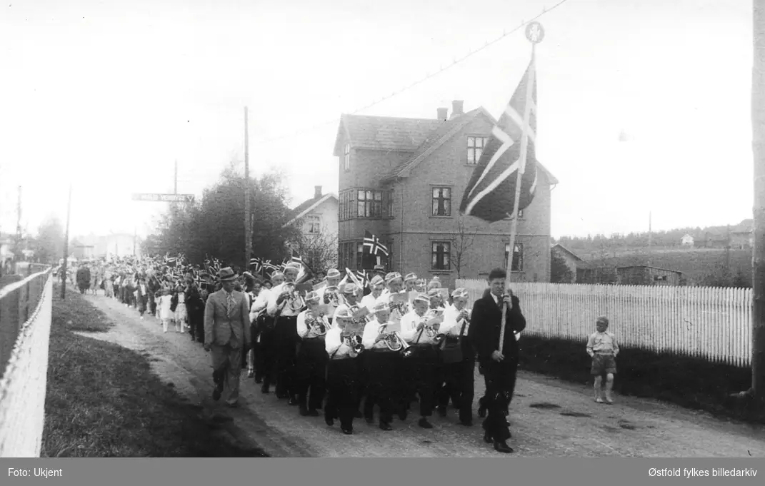Spydeberg Guttemusikk marsjerer foran 17. mai-toget i Spydeberg, Myrakrysset 1937-38.