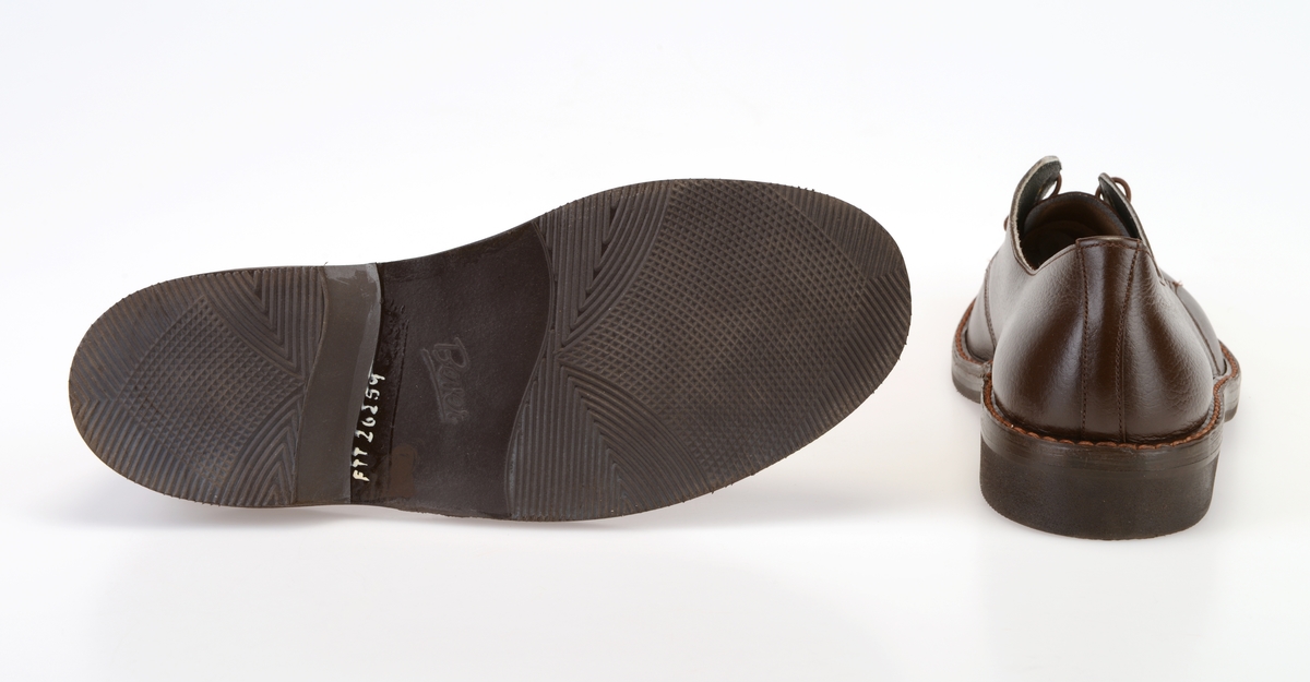 Et par barnesko i størrelse 38 i skoeske med silkepapir. Skoene er i mørkt brunt skinn med såler av svart gummi. Yttersålen har rutemønster og buet mønster. Ved hælen står det "Bever" i sålen. Skoene er randsydde med lysere brun tråd. I front er det 3 par hull med maljer for snøring. Under snøringen er det en enkel tunge av mørkt brunt skinn. Skoene har brune, runde skolisser. Skoene har innersåle av lær. De er foret med hvit tekstil i den fremre delen og grått lær (eller kunstlær?) i den bakre delen. Skoene ligger i en skoeske av papp som er stiftet sammen. På den ene kortsiden er det trykt på fabrikkens navn, varemerke og logo samt artikkelnummer og størrelse. Logoen er en sirkel med en Nord-pil igjennom. Logo og tekst er i rødt med påstemplet artikkelnummer og påskrevet størrelse i svart. Skoene er ikke brukt.
