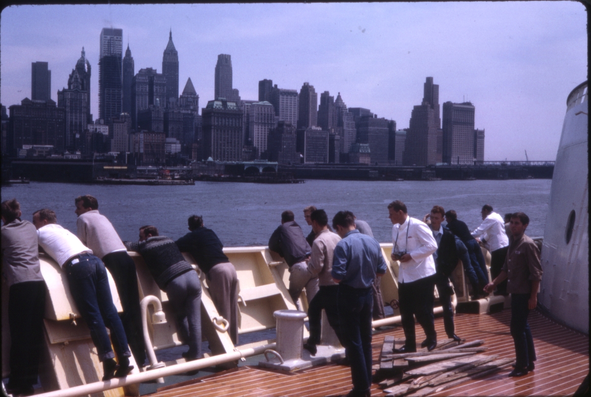 Passasjerer og mannskap om bord på cruiseskipet 'M/S Sagafjord' nyter utsikten over nedre Manhattan, New York, U.S.A. 'Sagafjord' Spring Cruise to Europe 1966.