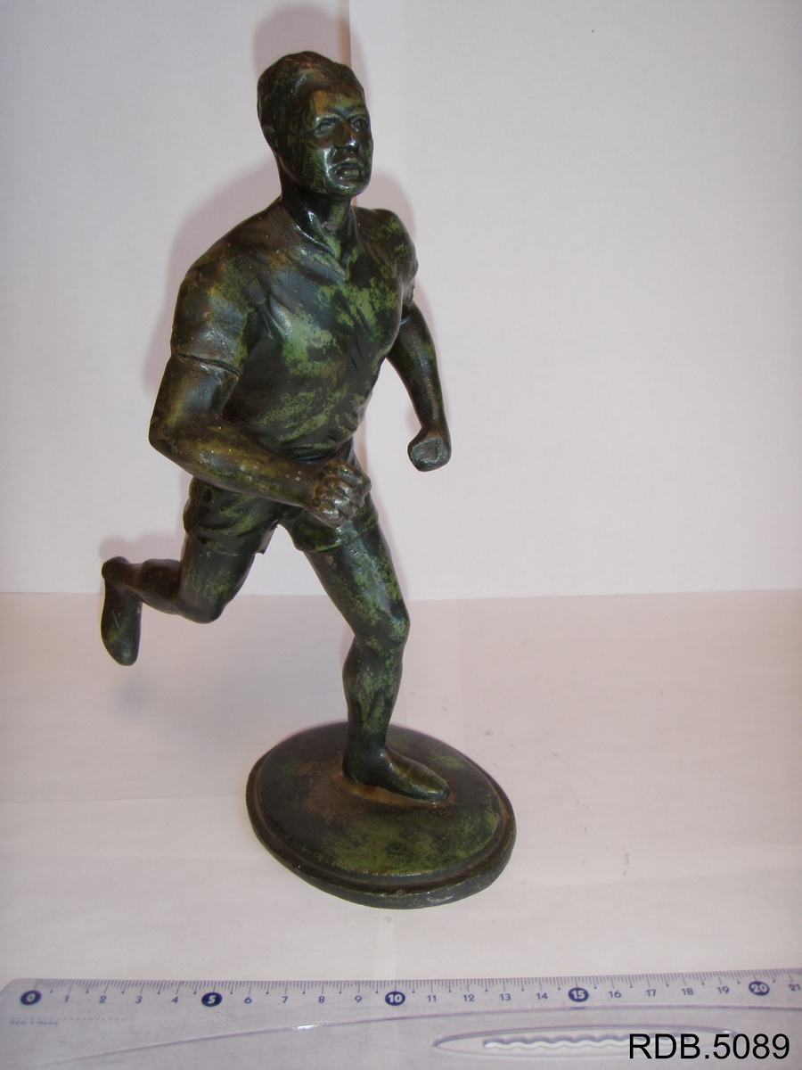 Statuett av en løper. Står på plate.