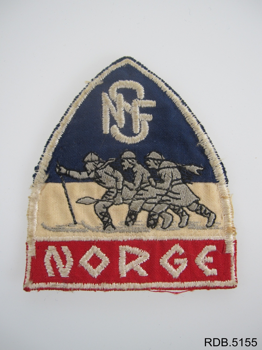 Jakkemerket er trekantet, og har en avrundet spiss oppover. Øverst er logoen til Norges skiforbund, som består av bokstavene NSF og et bilde av tre skiløpere. Nederst står det Norge.