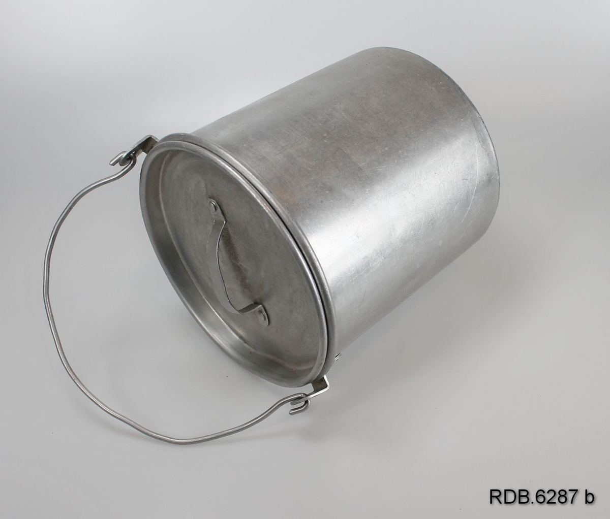 Et sølvfarget, sylindrisk 1-liters aluminiumsspann med hengslet hank og løst lokk med håndtak.