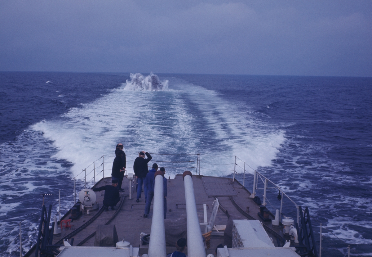 Bilden föreställer besättningsmedlemmar på akterskeppet av jagaren Öland som som iaktar en explosion bakom fartyget.