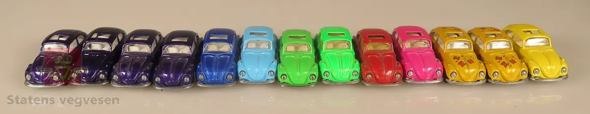 Samling av flere modellbiler. Alle er av samme produsent og produsert i lik tidslinje. 4 biler er lilla, 2 biler er blå, 2 biler er grønne, 1 bil er rød, 1 bil er rosa, 2 biler er gule med røde blomsterdekaler og 1 bil er gul. Alle er laget av metall og har en skala på 1:60