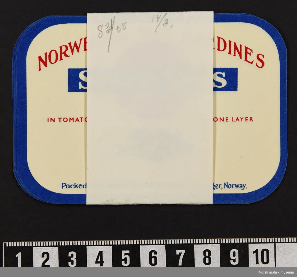 En bunke etiketter holdt sammen av et papirbånd. 

Etikettene har hvit farge, blå ramme og detaljer og tekst i rødt. Under varebeskrivelsen er en illustrasjon av en fisk og en tomat.