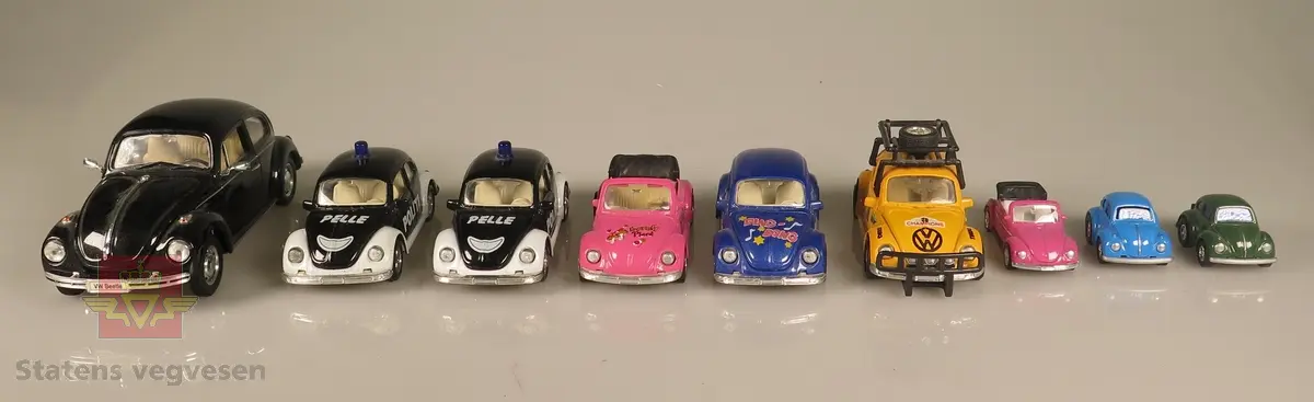 Samling av flere modellbiler.  2 biler er svarte utkledd som Pelle-politibil, 2 biler er blå, 2 biler er rosa, 1 bil er grønn, 1 bil er gul og 1 bil er svart Alle er laget av metall.