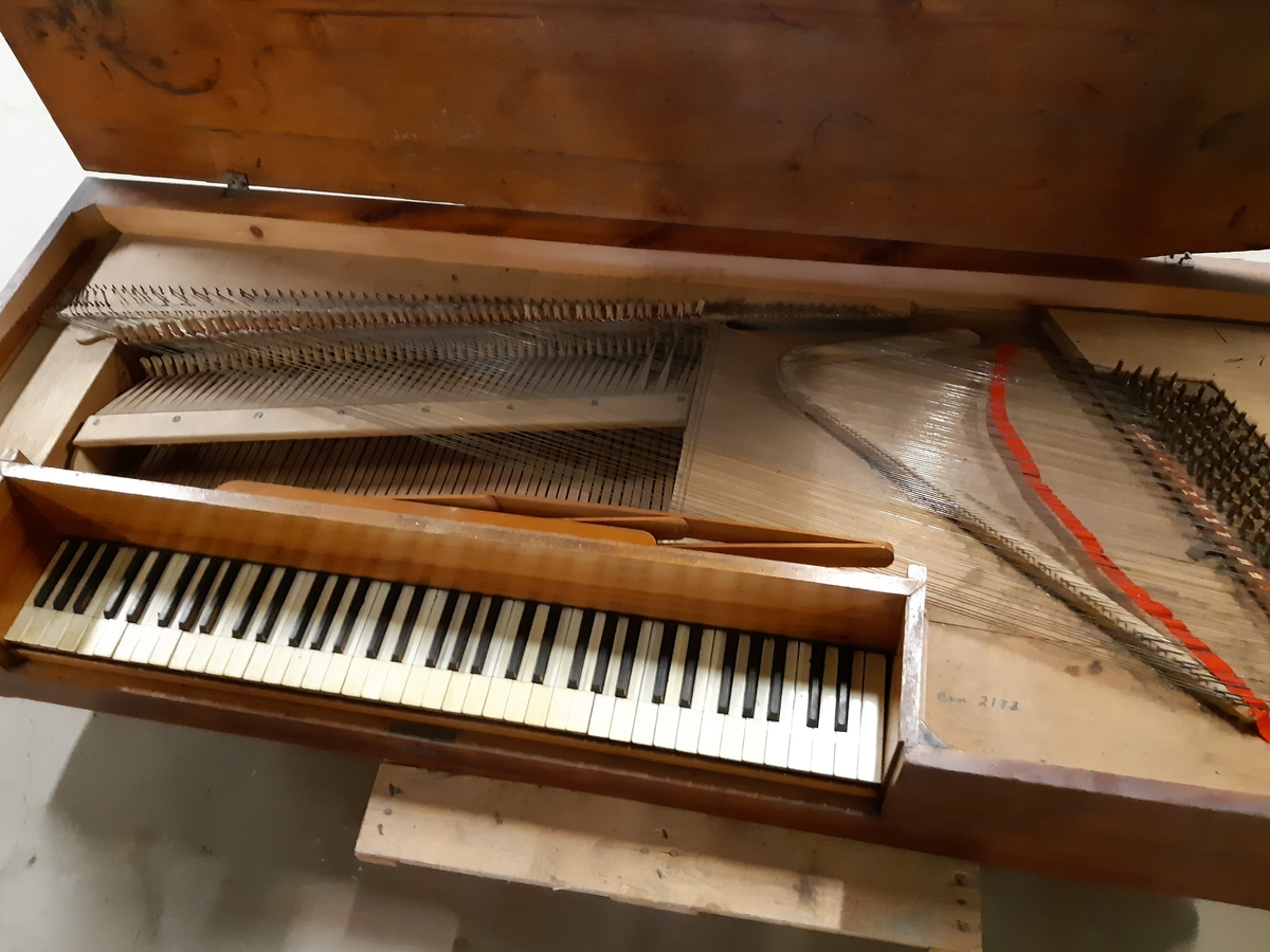 Rektangulært, kasseformet taffelpiano av vanlig type. 6 oktaver, delt klangbunnen til høyre, senere går den over hele instrumentet. Antagelig engelsk eller skandinavisk. Mangler understell. Lokk er løst.