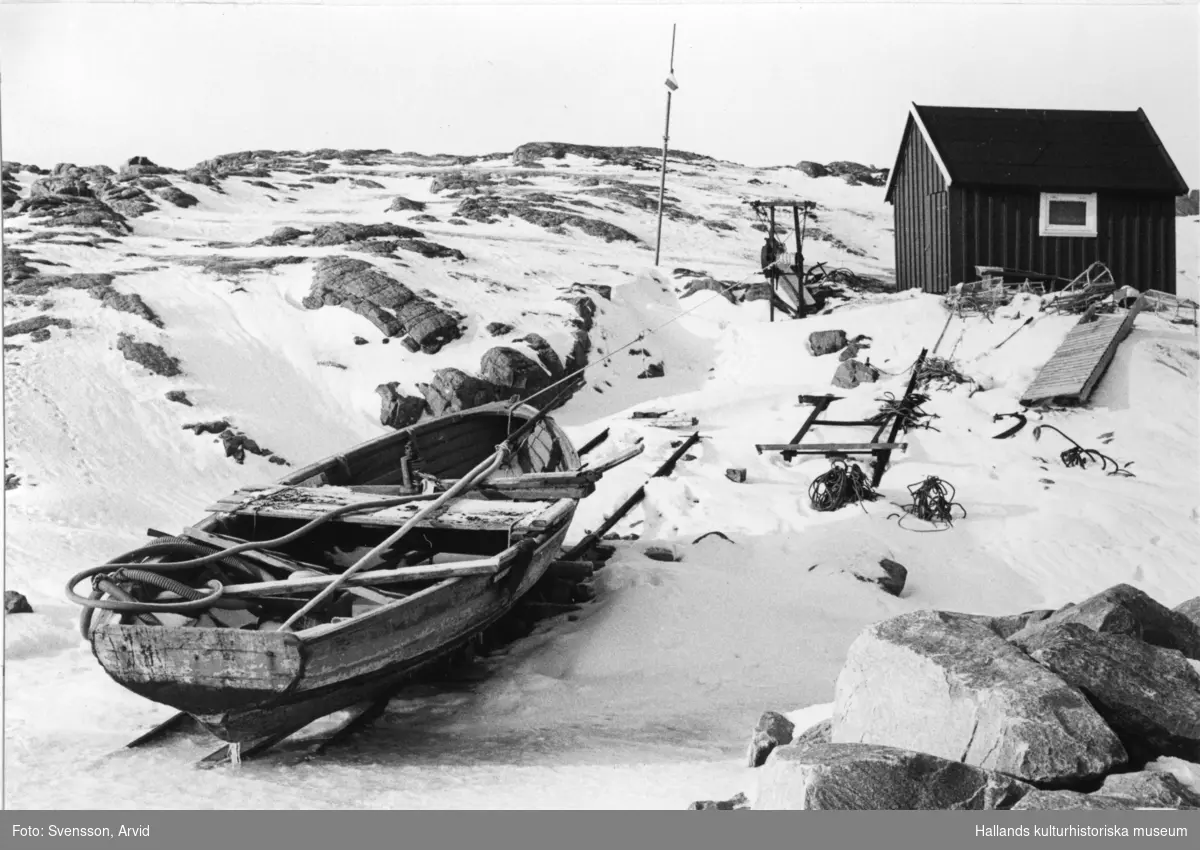 "Laxabåt uppdragen vid Långasand." I bakgrunden står en fiskebod och berget blottas här och var i snön.