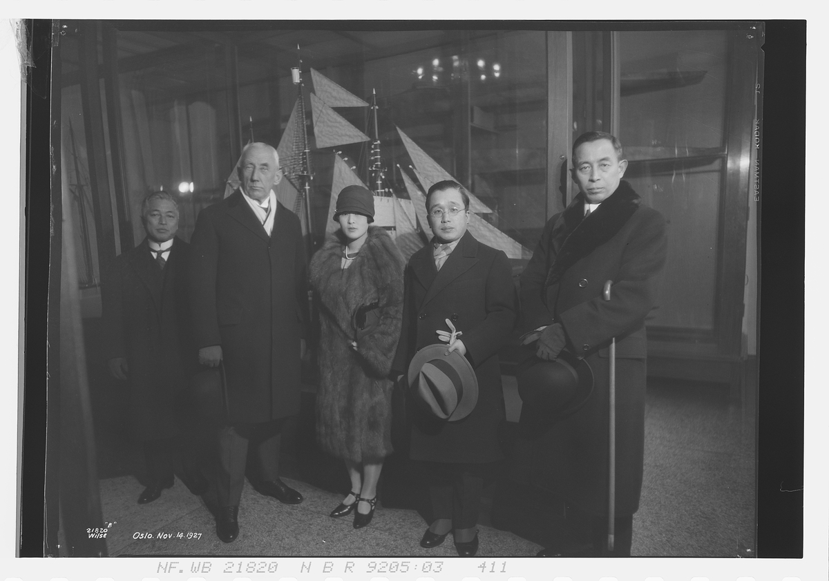 Roald Amundsen står sammen med prins Ri og prinsesse Masako. Polarskuta Fram står utstilt i bakgrunn. Datert Oslo 14/11-1927.