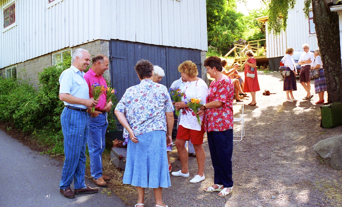 Invigning av Ekebackens Hantverksgård (tidigare John Lindströms möbelsnickeri) på Gamla Riksvägen 81, början av 1990-talet. Gun Flygare från Vuxenskolan (i blå kjol) avtackar Köksorkestern med blommor. Till höger (i röd blus) står Asta Axelsson (Vommedal).