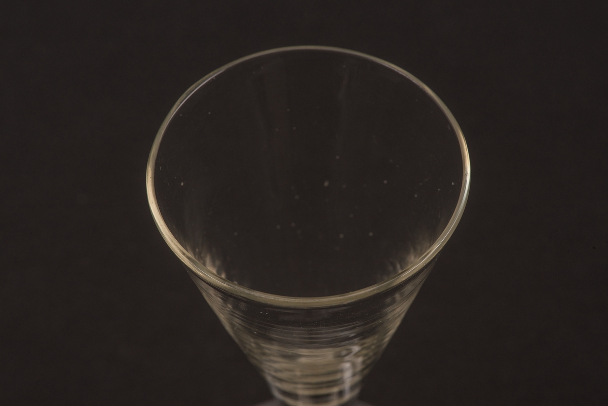 Brännvinsglas av klart glas utan dekor. Spetsglas med konisk kupa och stjälk på rund fot.