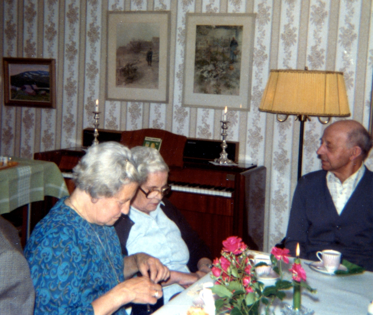 Två okända kvinnor och Anselm Zackrisson (1900 - 1987) sitter och fikar på Brattåshemmet år 1979. I bakgrunden ses en orgel.