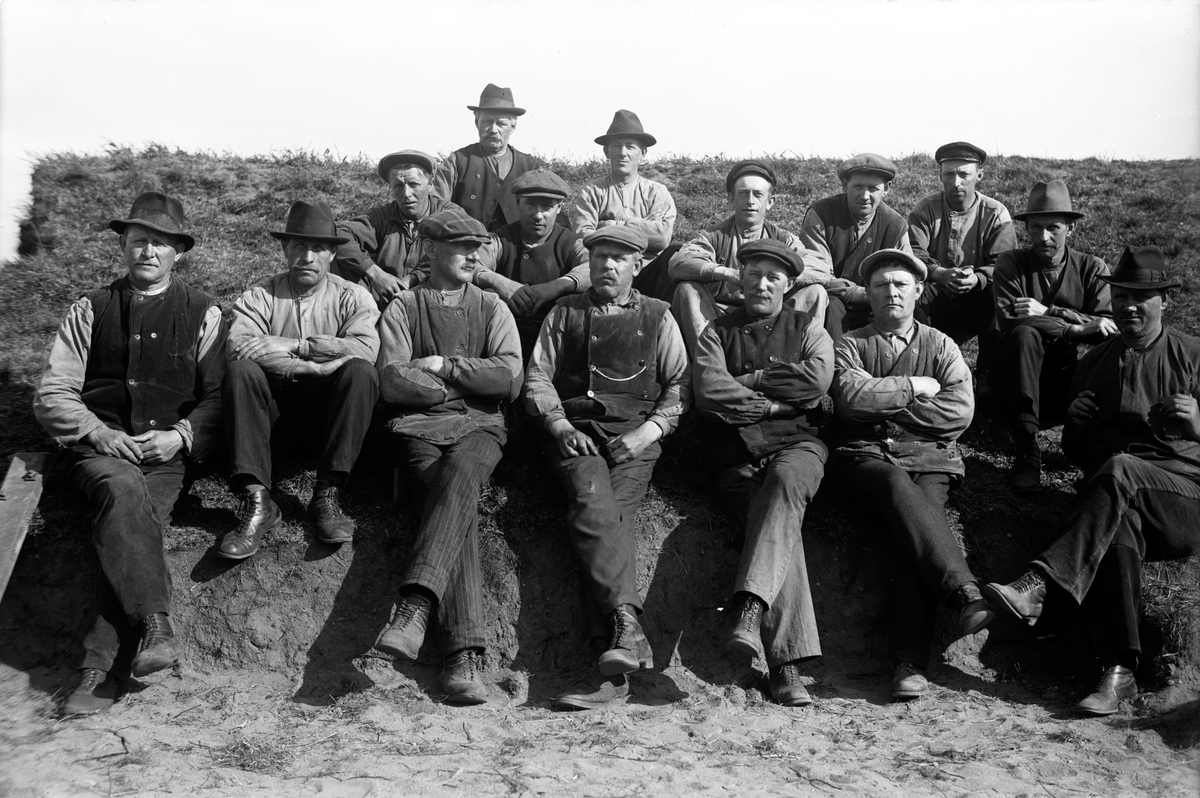 En grupp arbetsklädda män sitter i en sluttning.
