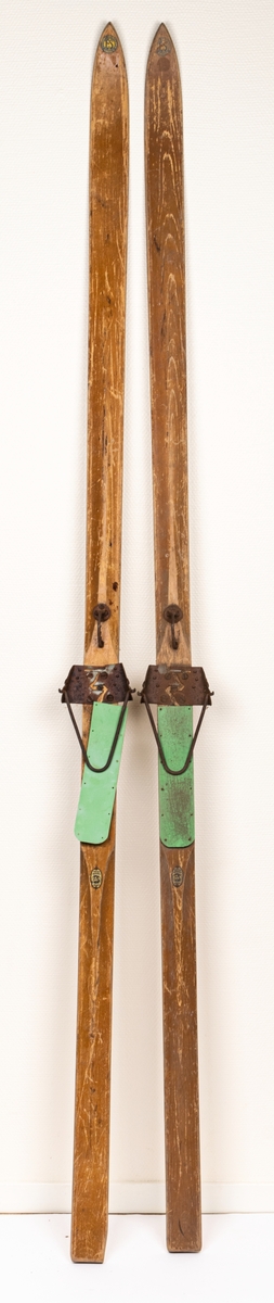 Ett par träskidor med bindningar i metall (rostiga). Märke påklistat med "Edsbyns Skidfabrik".