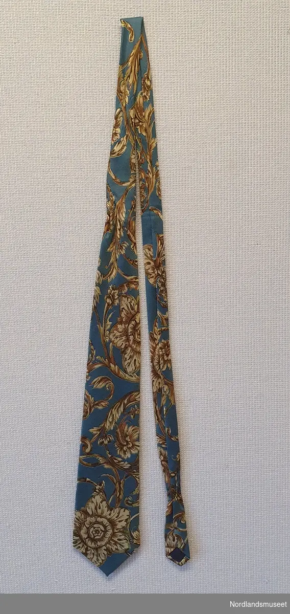 Blått slips med ornamentert blomsterrankemønster.