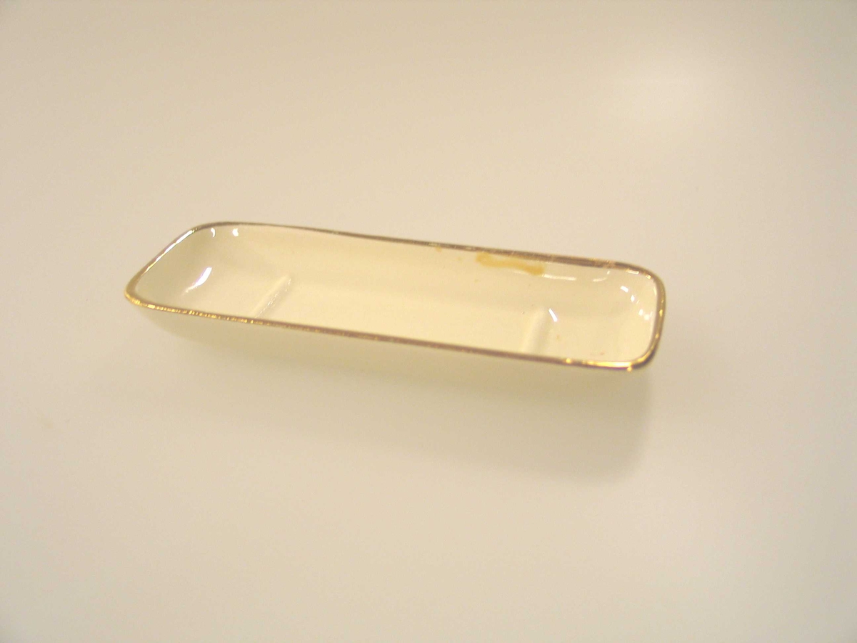 Såpeskål i dukkestørrelse i porselen med hank. Gulldekor øverst og på hanken. 