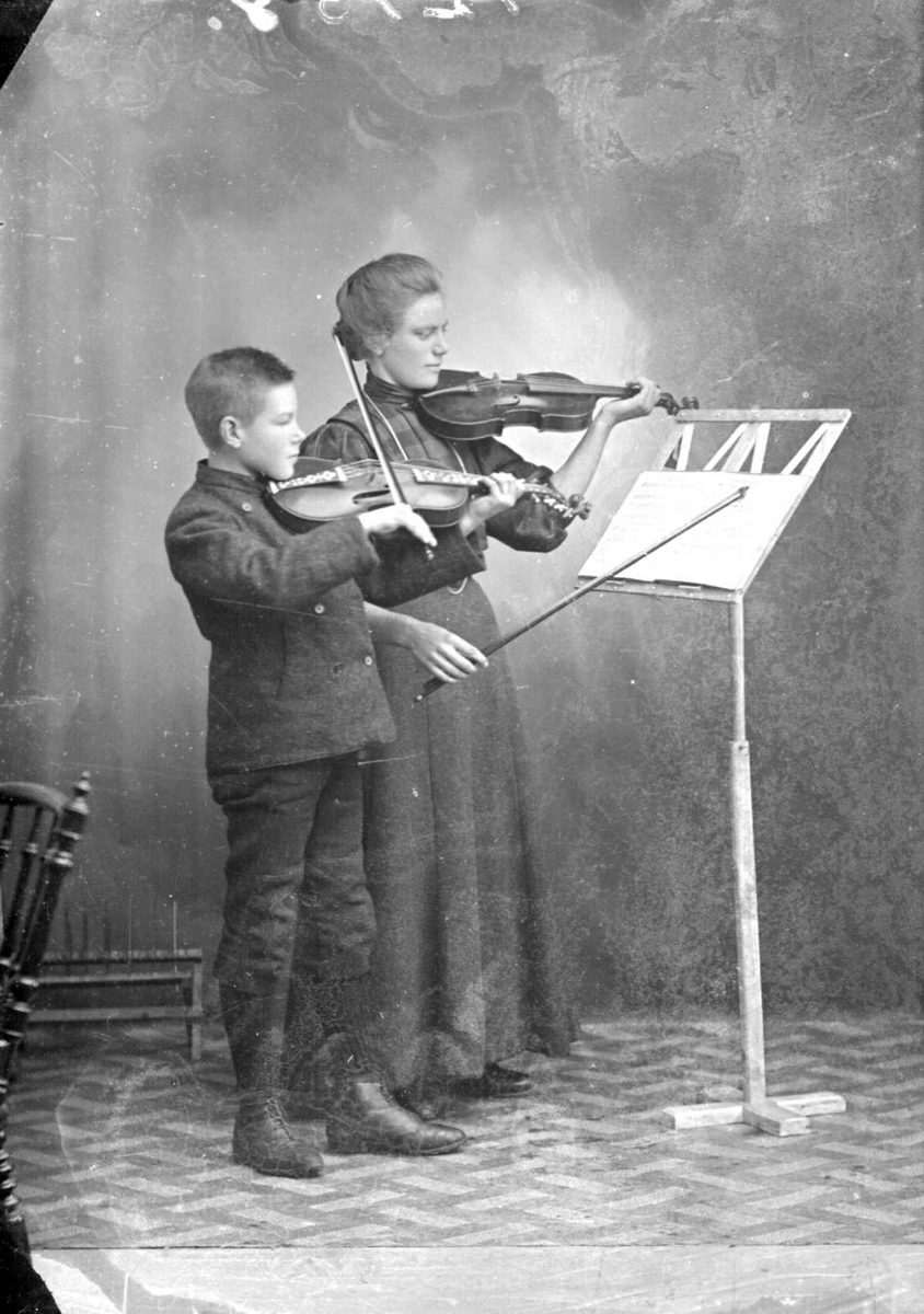 31.10.1909. Frk. Moldestad og Sverre Lie, Gruppebilde, kvinne og gutt med fiolin, notestativ.