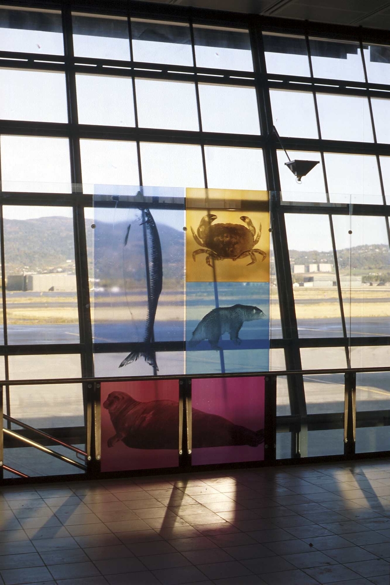 Motivene på glassveggene er reist mellom fasaden og søylerekkene, og kan betraktes både av de ventende, de som ferdes i avgangshallen og de som ankommer fra flyene.